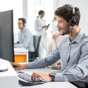 Smiling customer support agent with hands-free device working in call center