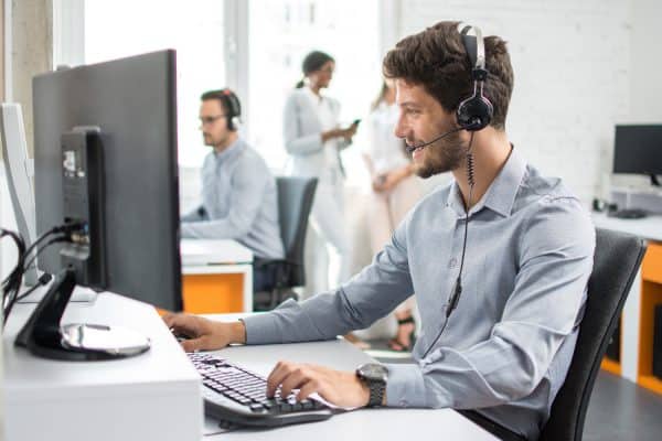 Smiling customer support agent with hands-free device working in call center